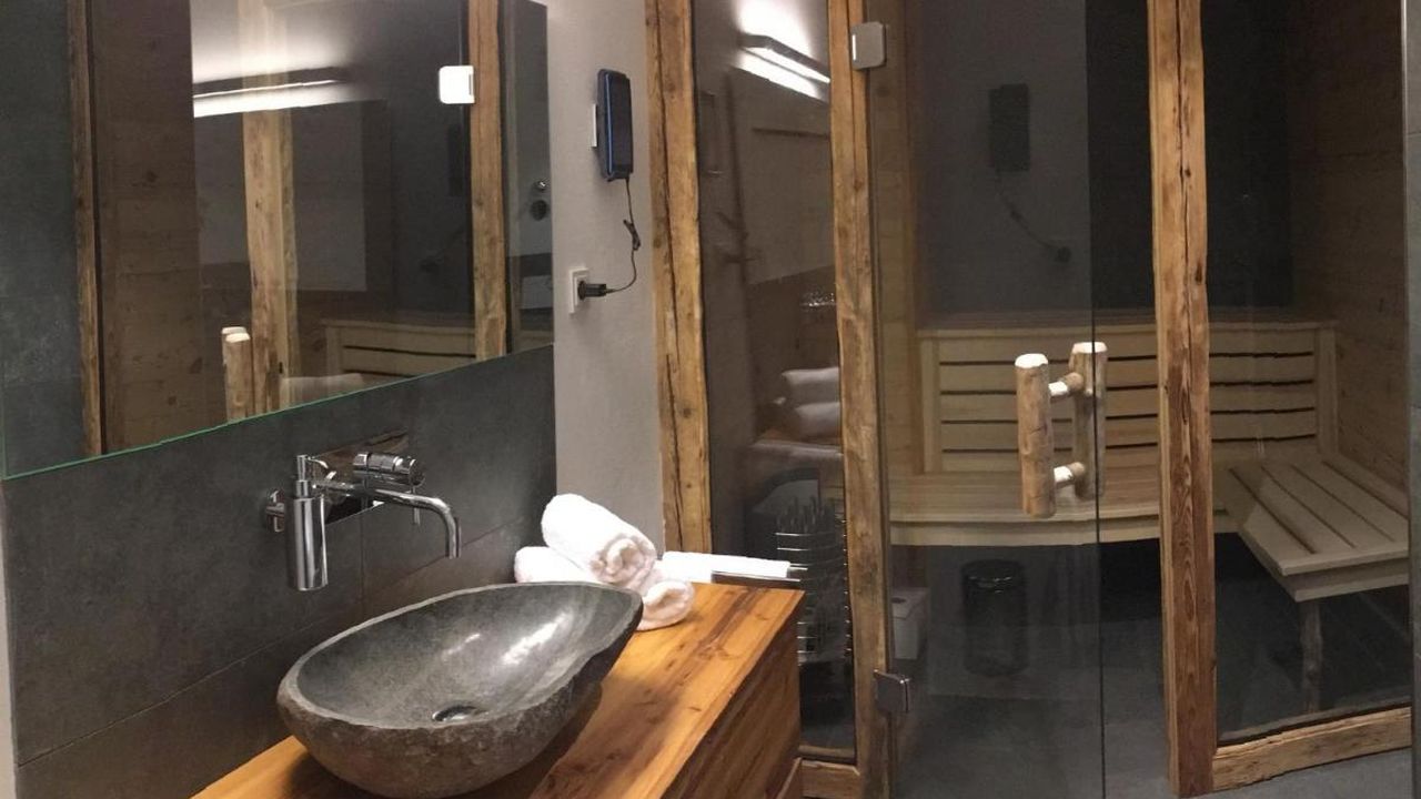 Badezimmer mit alpenländischer Design-Sauna und ebenerdiger Wellnessdusche Badezimmer mit alpenländischer Design-Sauna und ebenerdiger Wellnessdusche